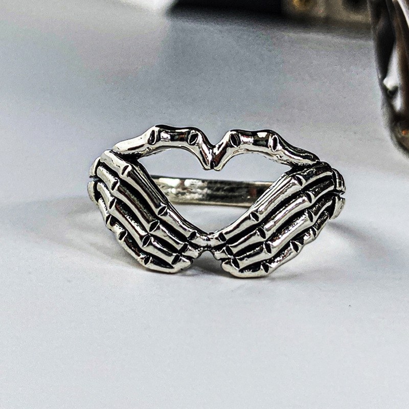 Silver-tone ring with hands forming a h…
